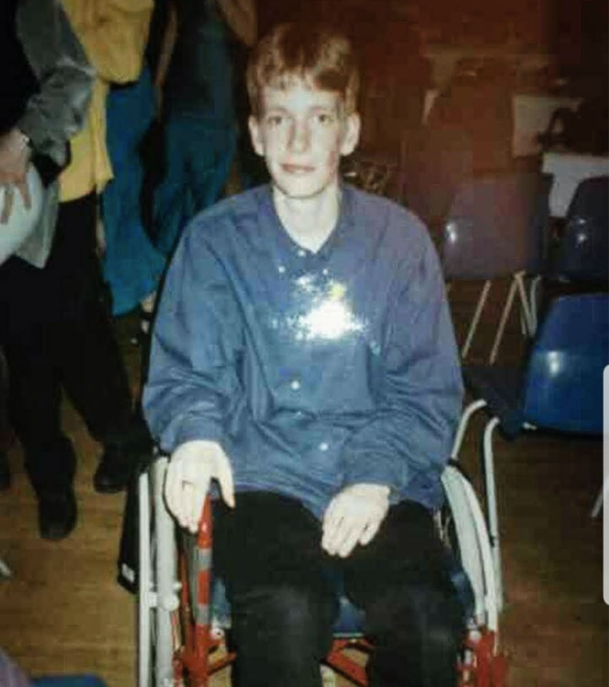 A blond haired boy, around 12 years of age, in a wheelchair.