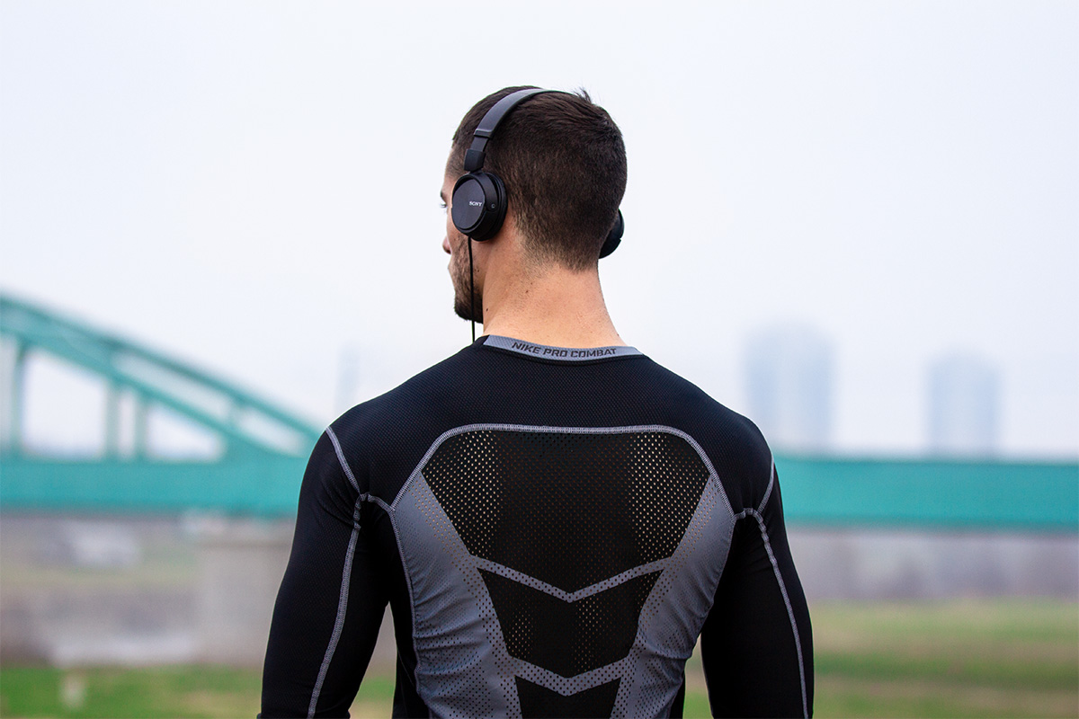 Man in the city, seen from behind. Wearing sports t-shirt and headphones.