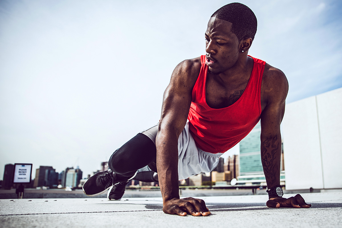 man doing pushups, arms fully extended, right knee reaching for right elbow