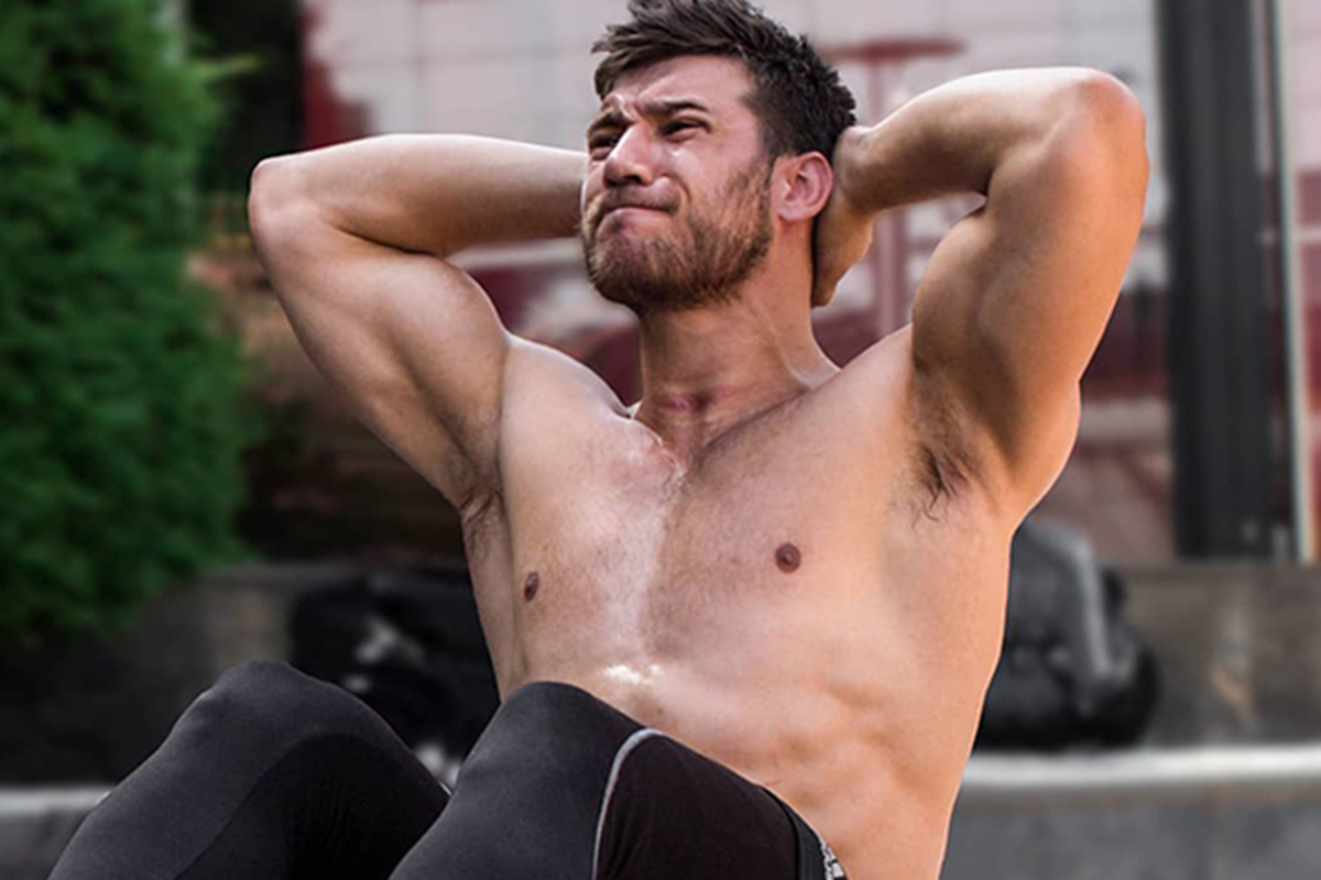 Man doing situps, chest half way to the knees, palms clasped behind head