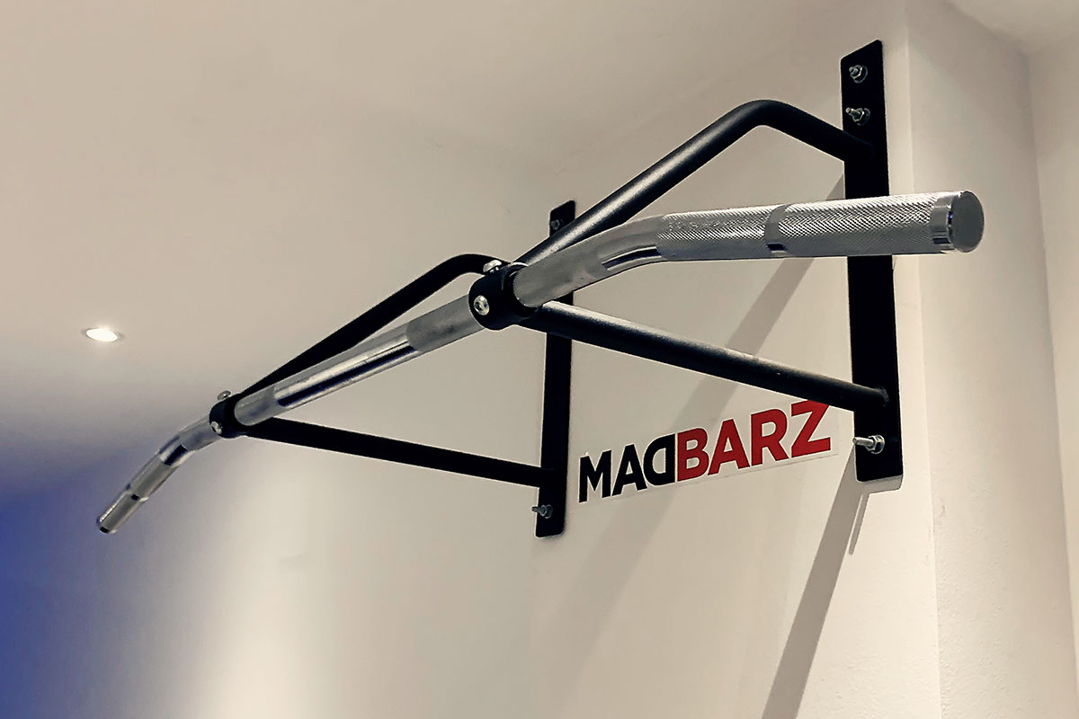 A wawll mounted pull up bar set on a white wall, with Madbarz sticker underneath it.