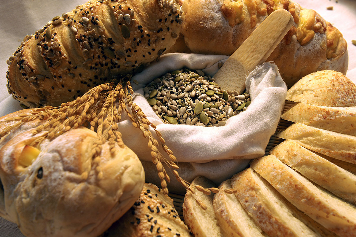 Various white breads rounded around a textile bag filled with pumpkin and sunflower seeds